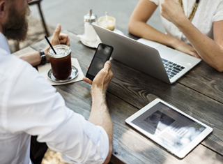 Man holding cell phone sitting across from woman with a laptop